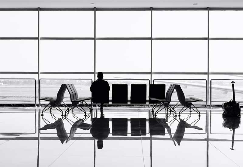 A lonely, stranded traveller sits alone in airport
